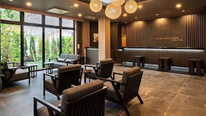 A modern hotel lobby with large windows, comfortable seating, and a reception desk.