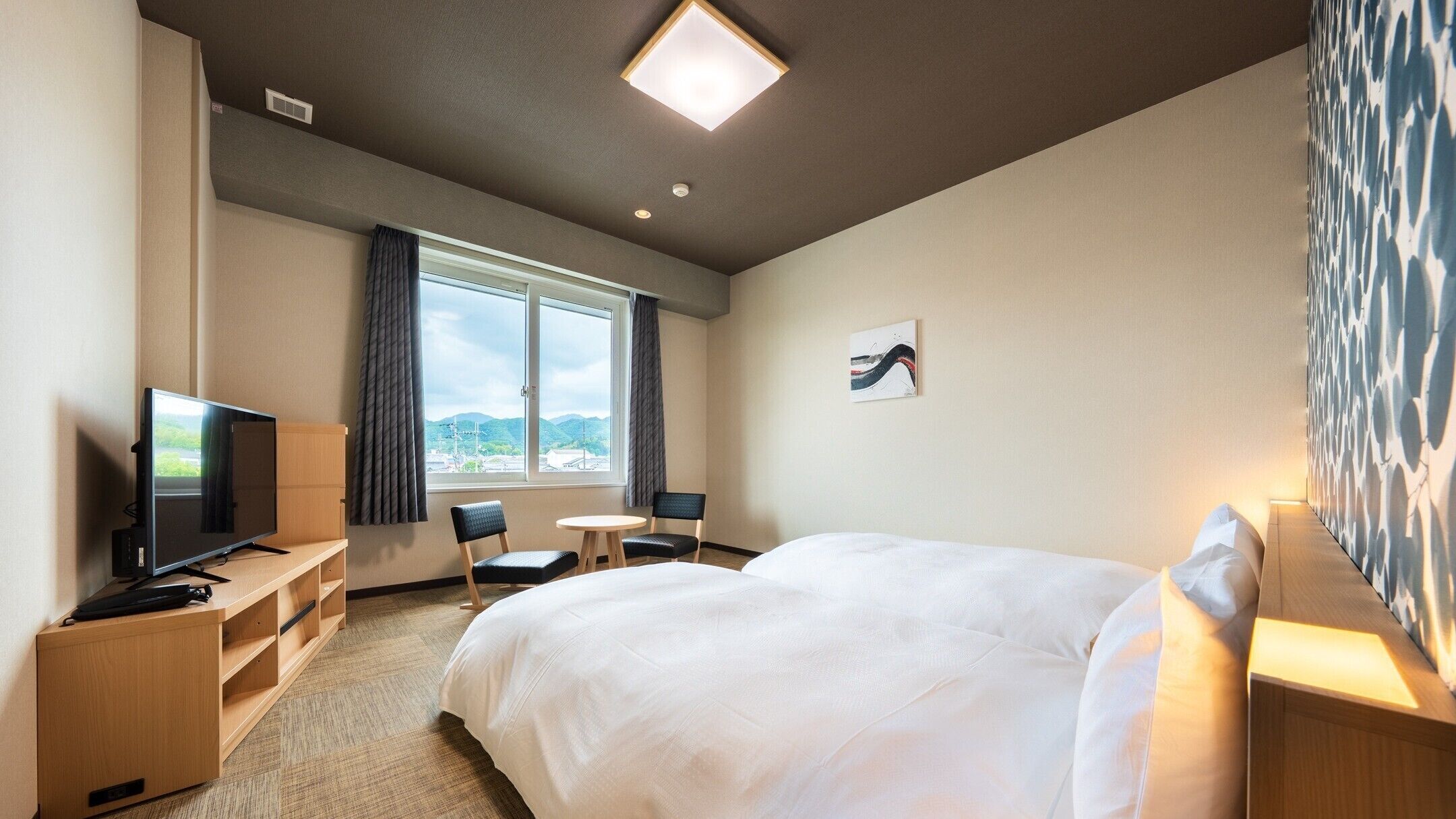 Une chambre d’hôtel avec un lit, une télévision, un bureau et une chaise.