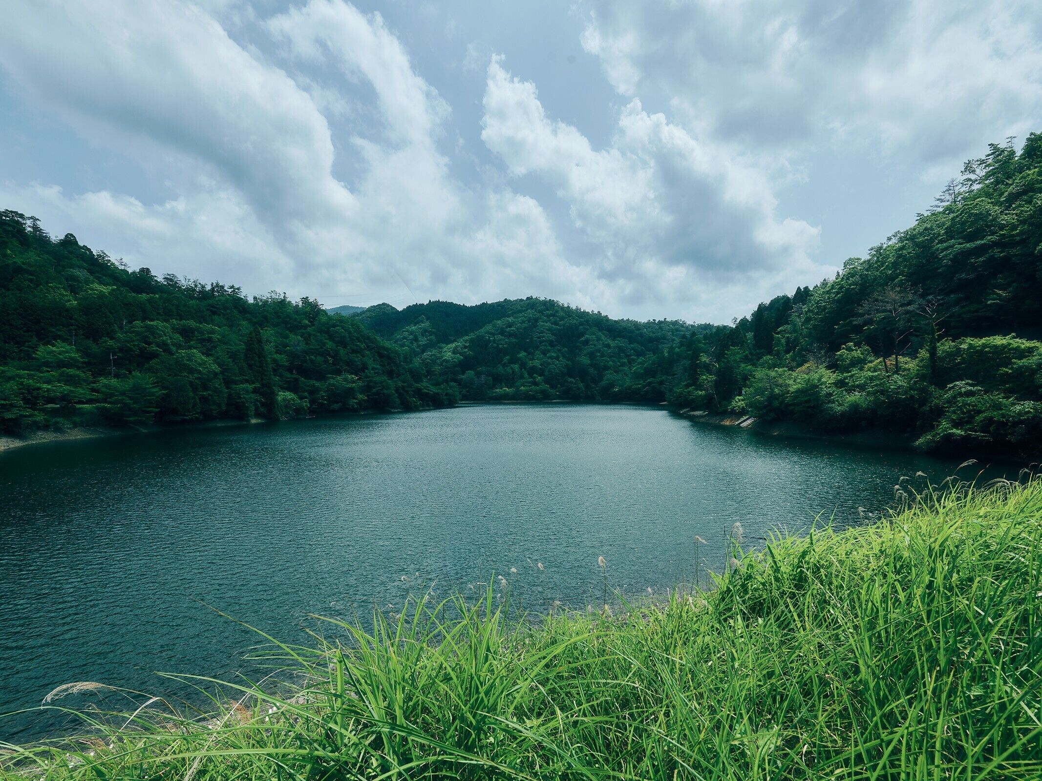 A serene lake surrounded by lush greenery and hills.