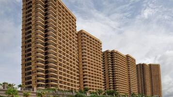 Un immeuble résidentiel de grande hauteur, doté de nombreux balcons, d’un style architectural uniforme et d’un espace paysager aménagé en premier plan.