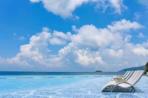 A beach with a clear sky and a single lounge chair.