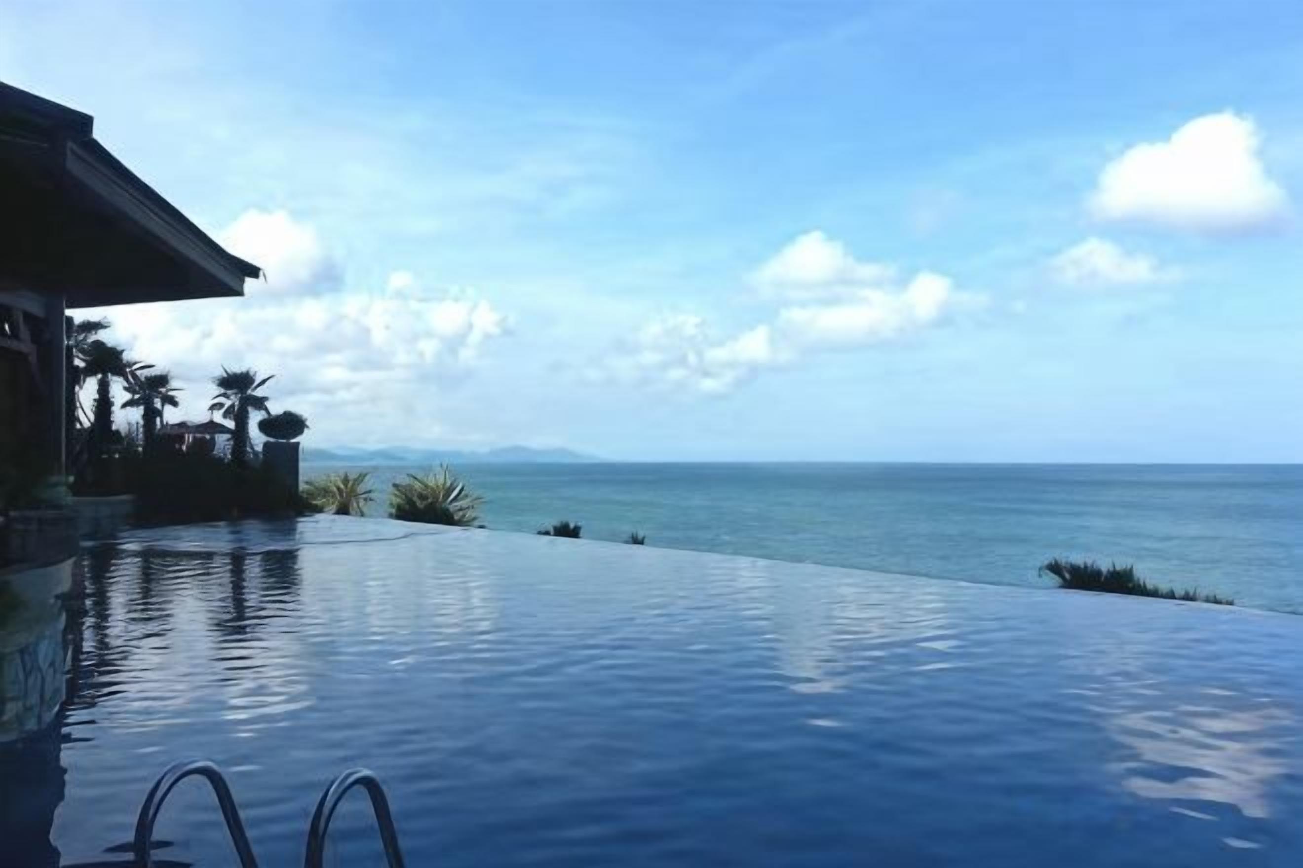 Una piscina infinita con vistas al océano y a las montañas.