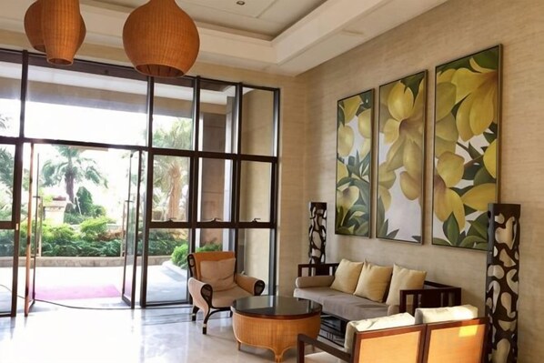 A spacious lobby with a sofa, armchairs, a coffee table, and large windows.