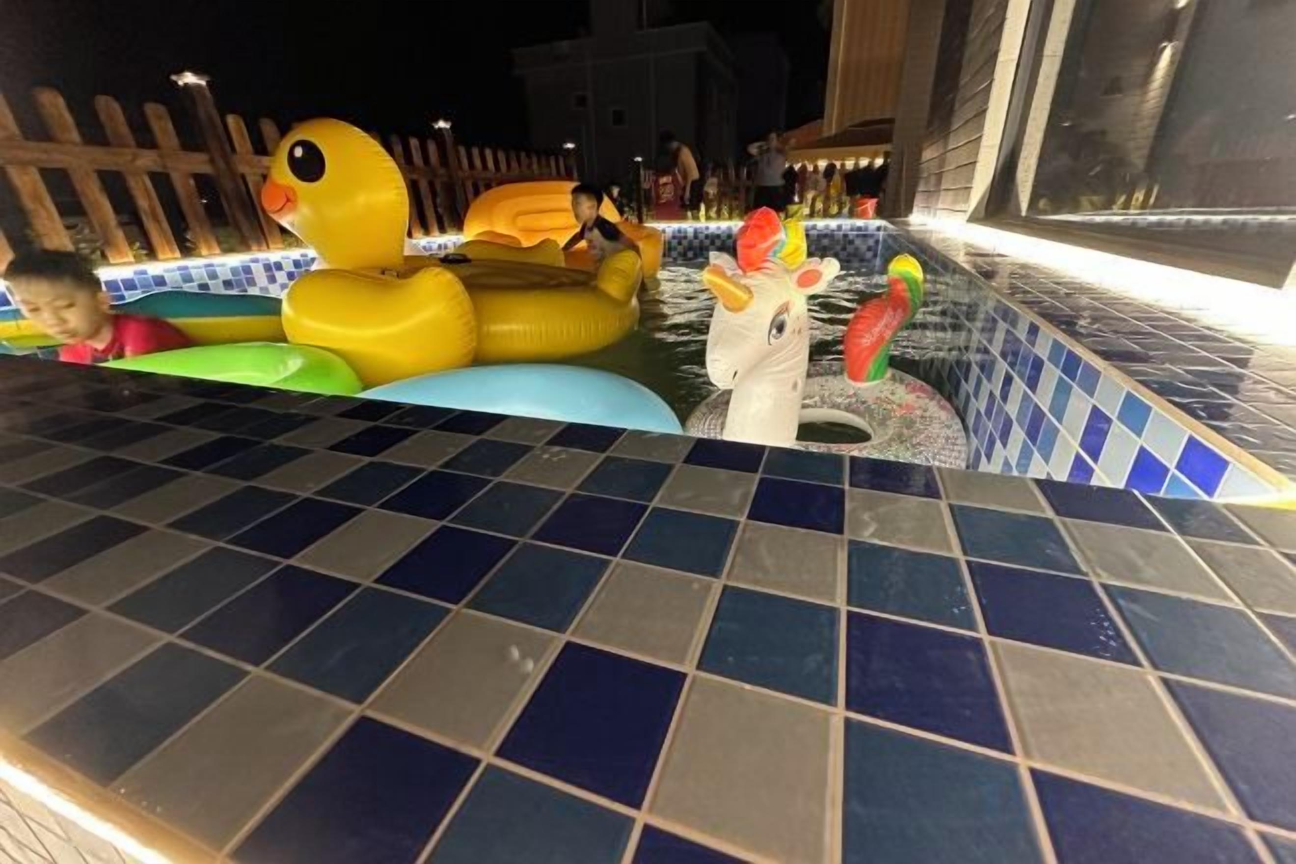 Zona de piscina con juguetes inflables y borde de azulejos.