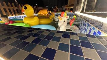 Zona de piscina con juguetes inflables y borde de azulejos.