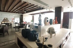 Un moderno vestíbulo de hotel con una recepción, área de descanso y un ventanal que proporciona luz natural.
