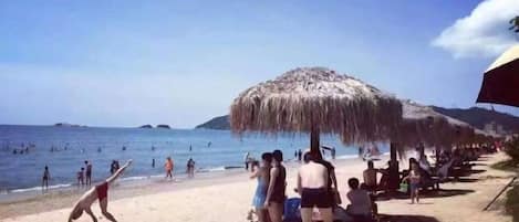 A beach with people, umbrellas, and a clear sky.