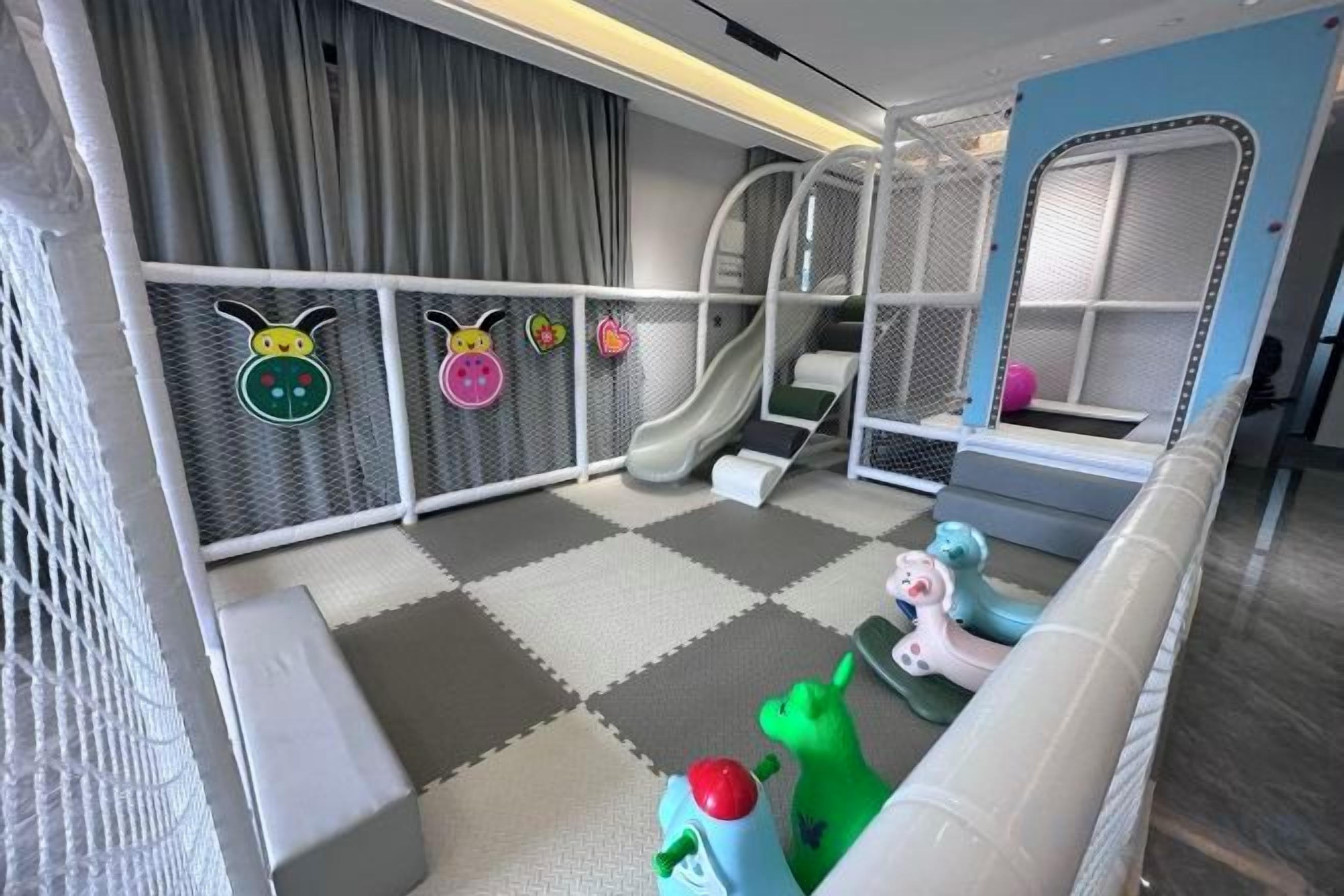 Zona de juegos infantiles con tobogán, juegos blandos y una zona de juego con red.