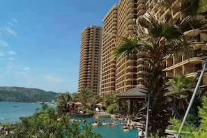 Un resort con piscina, palmeras y edificios altos.