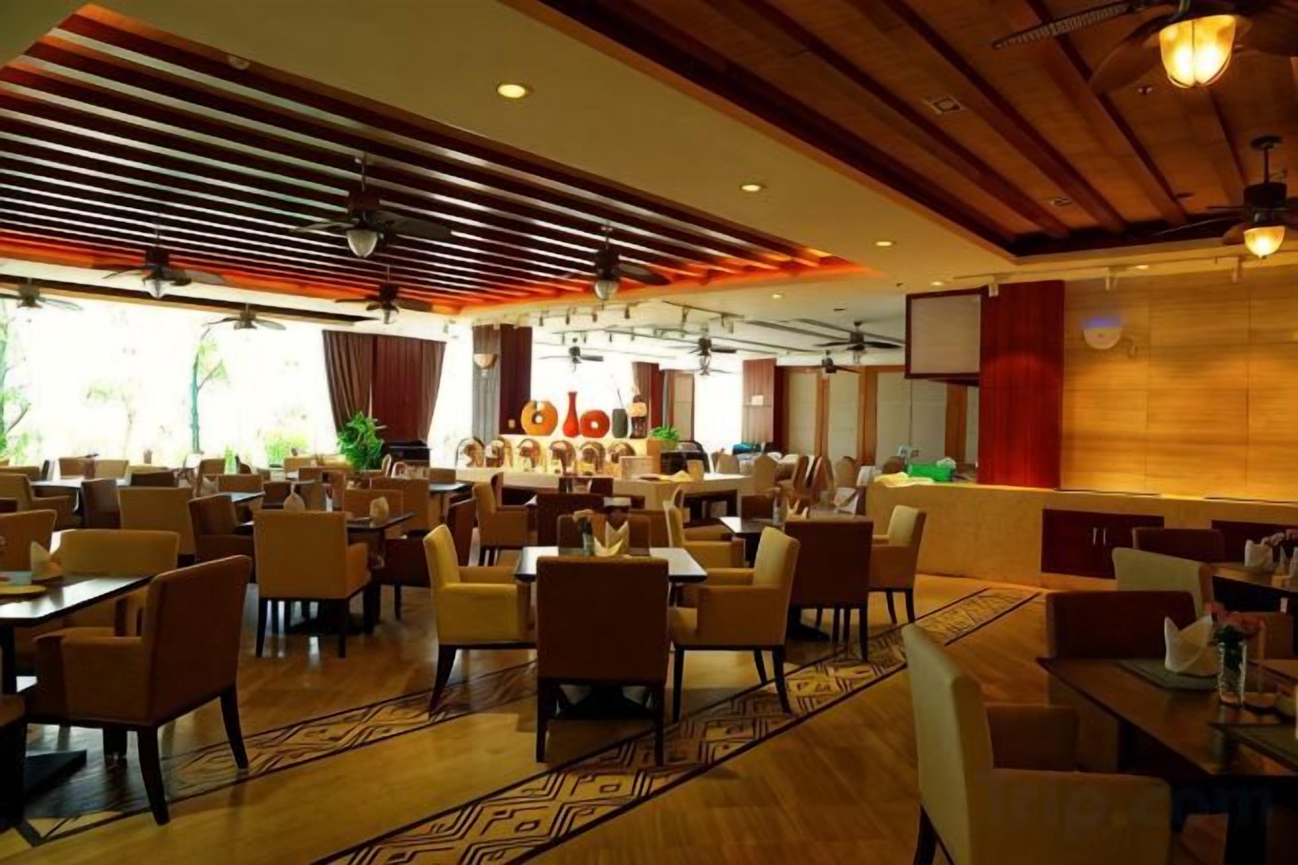 A spacious dining area with multiple tables and chairs, a bar area, and a view of the outdoors.