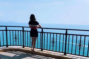 A person standing on a balcony with a railing, overlooking a body of water. - Honghai Bay Haihang Holiday Hotel (Huidong)