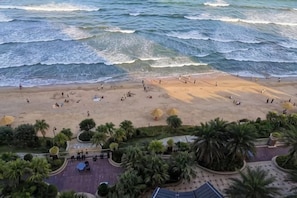 Une plage avec des gens, des palmiers et une vue sur l’océan.