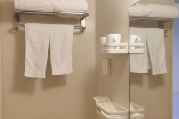 A bathroom with a mirror, a towel rack with folded towels, and a small shelf with toiletries. - Shijiangzhuang Youjia Inn Eryuan Branch (Shijiazhuang)
