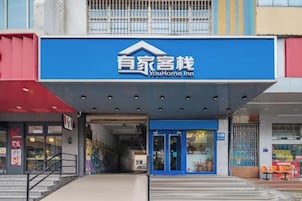 A hotel entrance with a blue sign, a covered entrance, and a staircase leading up.
