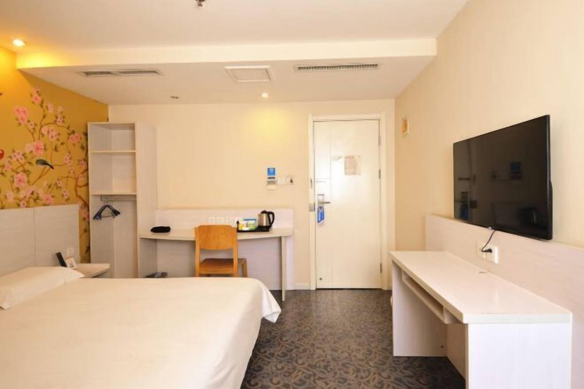 Ein Hotelzimmer mit Bett, Schreibtisch mit Stuhl, Fernseher und Kleiderschrank.