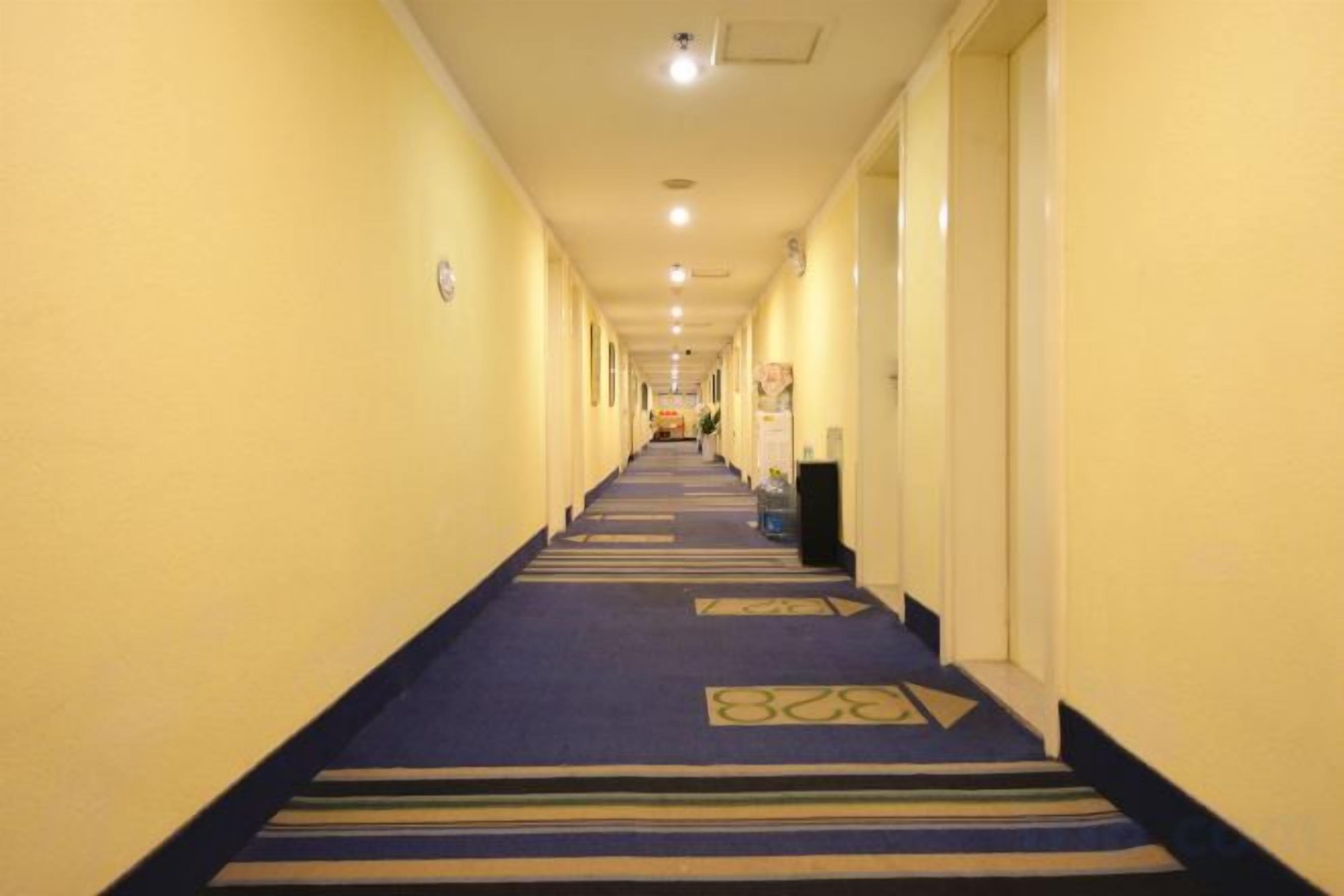 Ein Hotelkorridor mit Teppichboden, Türen auf beiden Seiten und einer Deckenleuchte.