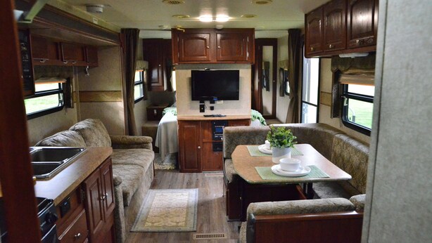 A compact RV interior with a kitchenette, a dining area, and a TV mounted on the wall. - Casa Coqui Camper, with WiFi, & AC, 3 miles from Falls Creek Falls State Park (Pikeville)