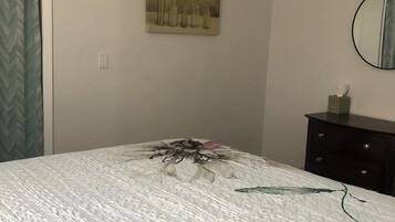 A bedroom with a bed, a painting on the wall, a dresser, and a mirror.