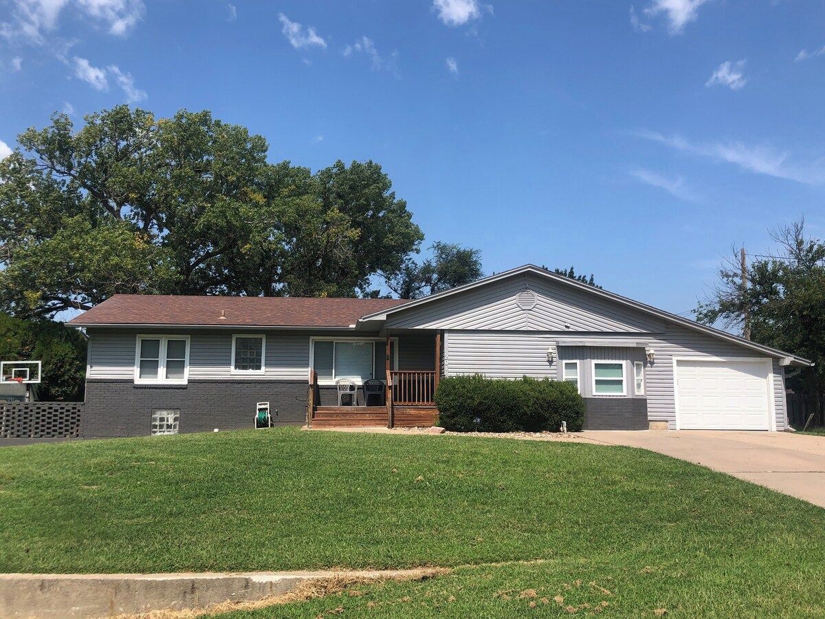 A two-story residential house with a front porch, a garage, and a well-maintained lawn.