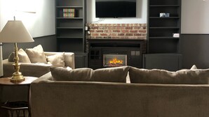 Ein Wohnzimmer mit Kamin, einer Couch, einer Lampe und Bücherregalen.