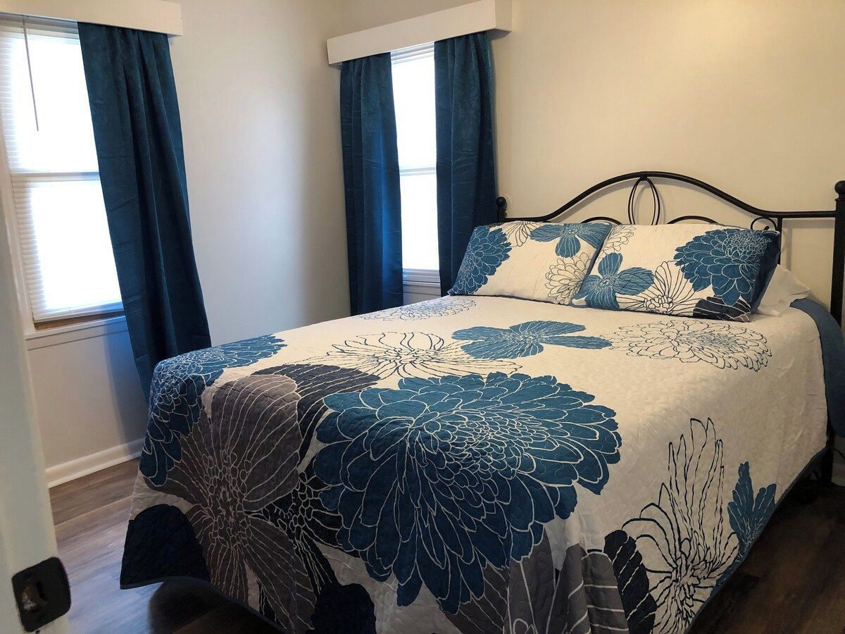 Un dormitorio con cama, cortinas oscuras y ventana.