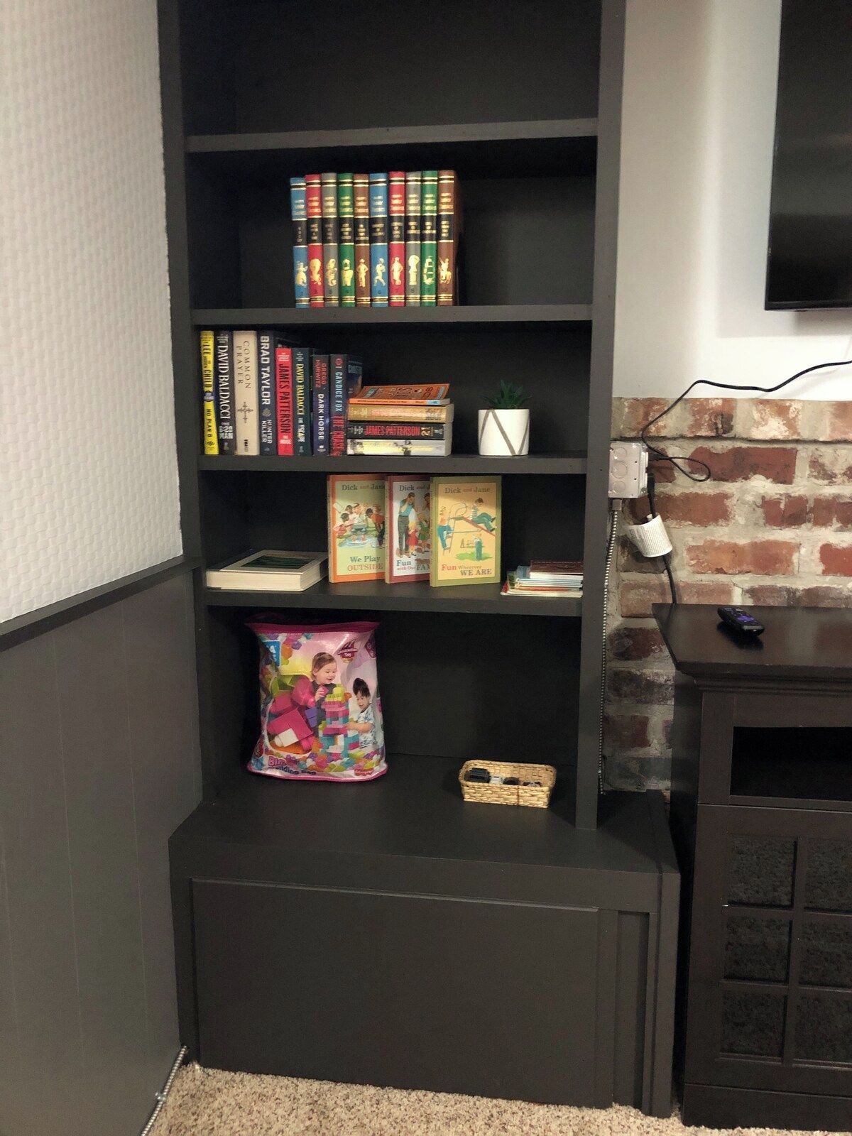 A bookshelf with various books and a small plant.