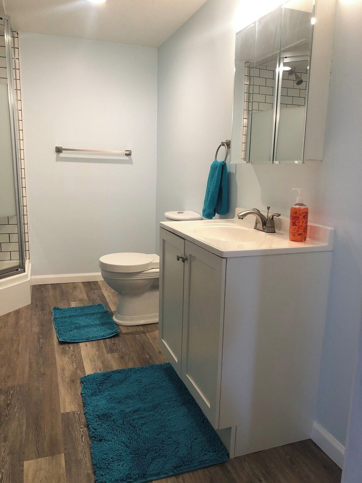 A bathroom with a shower, toilet, sink, and cabinet.