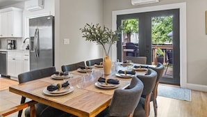 Un espace repas moderne avec une table en bois dressée pour six personnes, entourée de chaises à revêtement gris.
