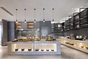 A modern kitchen with a central island, pendant lighting, and brick-patterned walls. - Wanda Yue Hotel Bengbu South Station (Bengbu)