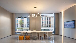 A modern conference room with a long table, six chairs, and two orange stools. - Wanda Yue Hotel Bengbu South Station (Bengbu)