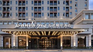A hotel entrance with a modern facade, large windows, and a sign with Chinese characters. - Wanda Yue Hotel Bengbu South Station (Bengbu)