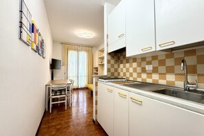 A compact kitchen with white cabinets, a sink, and a tiled backsplash.