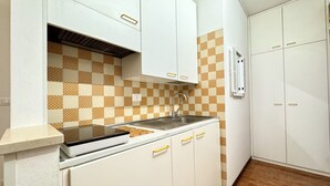 A kitchen with white cabinets, a checkered backsplash, and a stainless steel sink.