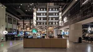 Un intérieur moderne avec un comptoir d’accueil central, plusieurs espaces de détente et un bar.