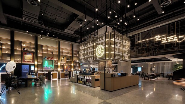 Un intérieur moderne avec un bar central, de nombreux espaces de détente et une variété d’étagères.