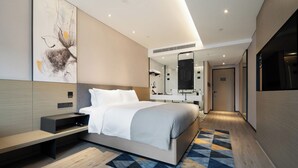 Une chambre d’hôtel moderne avec un grand lit, une table de chevet, un miroir et un téléviseur fixé au mur.