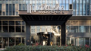 L’entrée d’un hôtel, avec une façade moderne en verre et une enseigne indiquant « Wanda Moments ».