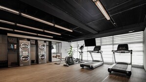 Une salle de sport moderne équipée de tapis de course, d’un vélo d’appartement et d’un rameur.