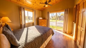 A bedroom with a bed, wooden ceiling, a ceiling fan, a dresser, and a view of the outdoors. - 3 Bedroom Cabin 3 Beach front (Isle)
