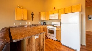 A kitchen with wooden cabinets, a granite countertop, a white refrigerator, and a stove. - 3 Bedroom Cabin 3 Beach front (Isle)