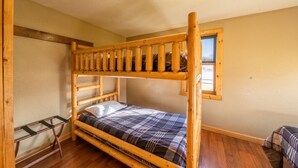 A bunk bed room with a wooden frame, a small table, and a window. - Cabin 4 at the Lake - 2 bedrooms (Isle)