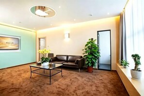 A hotel lobby with a sofa, coffee table, potted plants, and a framed picture on the wall. - Yayuan Tanglang Hotel (Shenzhen Nanke University Shenzhen Dalihu Subway Station Branch) (Shenzhen)