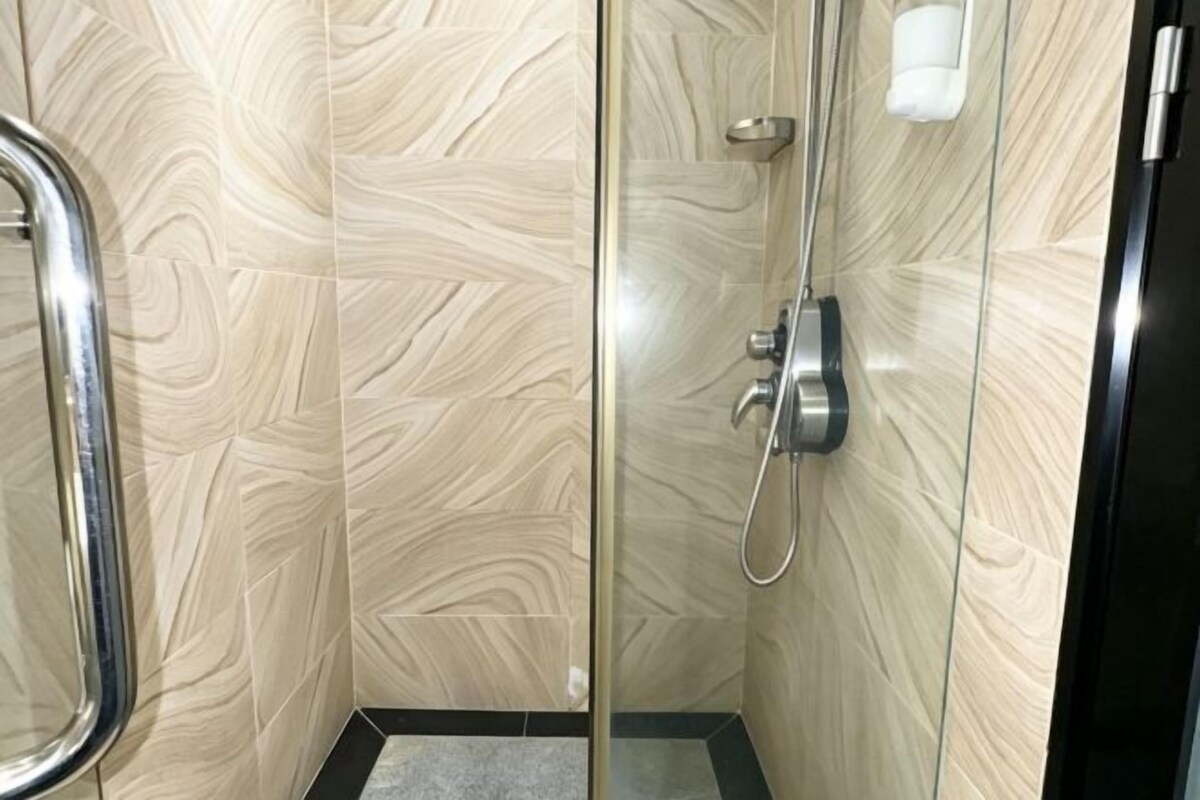 A glass-enclosed shower stall with a handheld showerhead and a wall-mounted faucet.