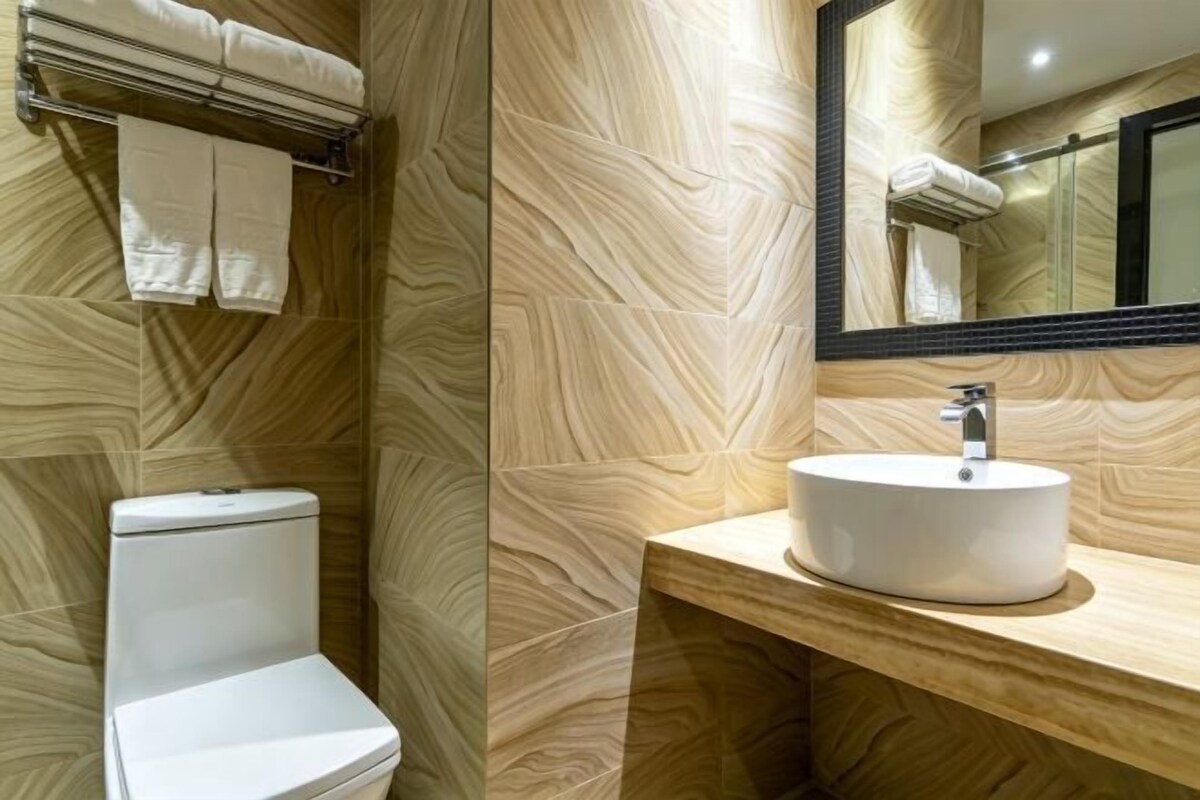 A bathroom with a toilet, sink, mirror, and towel rack.