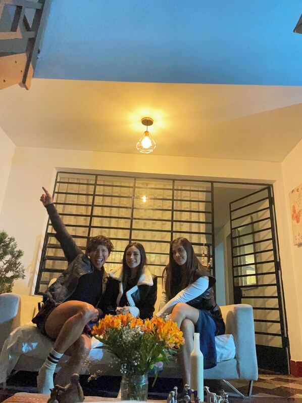 A room with a sofa, a decorative vase with flowers, and a hanging light fixture.
