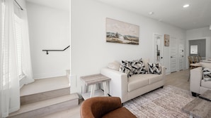 Un salon moderne avec un escalier, un ensemble de canapés et un coin repas.