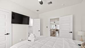 Une chambre d’hôtel avec un grand lit, des murs blancs et un téléviseur à écran plat fixé au-dessus du lit.