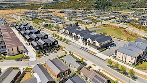 A residential area with modern houses, roads, and a hilly backdrop. - Mountainview Escape | Stylish, BBQ, and Parking (Wānaka)
