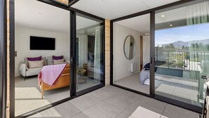 A modern interior with a bed, sofa, and a dining area. - Mountainview Escape | Stylish, BBQ, and Parking (Wānaka)