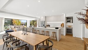 Une cuisine moderne dotée d’un îlot central, d’une table à manger en bois et de tabourets de bar.